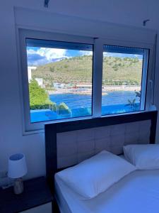 1 dormitorio con 2 ventanas con vistas al agua en Fabeno Villa, en Sarandë