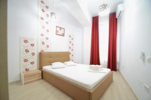 - une chambre avec un grand lit et des rideaux rouges dans l'établissement Uptown Residence Apartments, à Bucarest