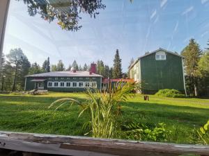 une grande grange verte et une maison dans un champ dans l'établissement Taigaschool Eco Hotel, à Virrankylä