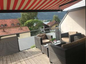 a balcony with wicker furniture and an american flag at FeWo mit Seeblick in Bodensdorf