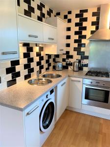 una cucina con armadi bianchi e una lavatrice/asciugatrice di Firpark City Apartment - 2 Bedrooms a Glasgow