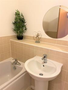 e bagno con lavandino, specchio e vasca. di Firpark City Apartment - 2 Bedrooms a Glasgow