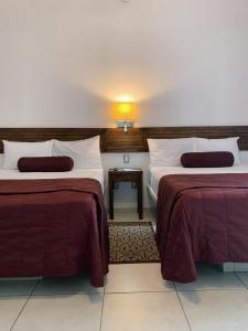 a hotel room with two beds with red sheets at HOTEL MI SOLAR EJECUTIVO in Uruapan del Progreso