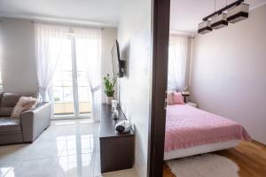 um quarto com uma cama rosa e um sofá em Apartament Masuria em Ełk