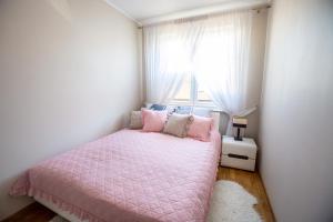 um quarto com uma cama rosa e uma janela em Apartament Masuria em Ełk