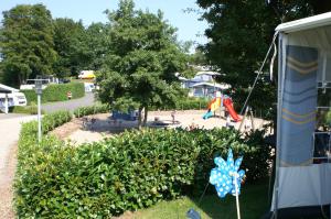 een park met een speeltuin en een boom en struiken bij Fjordlyst Camping & Cottages in Aabenraa