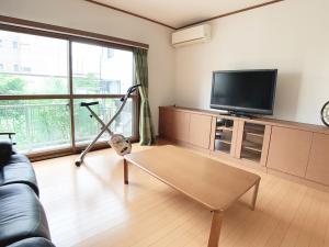 ein Wohnzimmer mit einem Couchtisch und einem Flachbild-TV in der Unterkunft Itsukaichi First Villa Hiroshima in Hiroshima