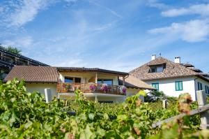 a house with a balcony with flowers on it at Weinhof am See in Caldaro