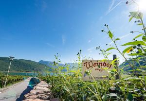 a sign for a winery in a field of flowers at Weinhof am See in Caldaro