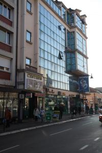 un bâtiment dans une rue où les gens marchent sur le trottoir dans l'établissement Centrum Sobe Rooms Čačak, à Čačak