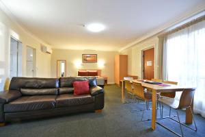 a living room with a leather couch and a table at Abel Tasman Motor Inn in Dubbo