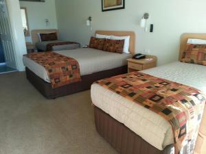 a hotel room with two beds and a chair at Abel Tasman Motor Inn in Dubbo