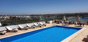 - une piscine sur le toit d'un immeuble avec des chaises et des tables dans l'établissement Hotel Rabat - A member of Barceló Hotel Group, à Rabat