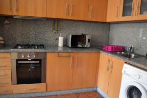 cocina con armarios de madera, fregadero y microondas en Casa D'avo, en Gerês