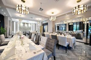 a restaurant with white tables and chairs and chandeliers at Pensiunea Nora Prestige in Timişoara