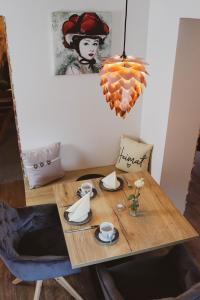 a wooden table with cups and saucers and a painting at Pension Heimat in Ottenhöfen