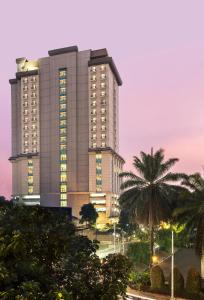 un grand bâtiment avec un palmier devant lui dans l'établissement Swiss-Belhotel Bogor, à Bogor