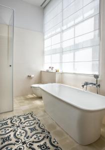 baño con bañera blanca y ventana en The Norman Tel Aviv, en Tel Aviv