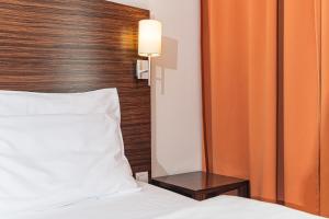 una camera con letto bianco e testiera in legno di Hotel Euro a Pardubice