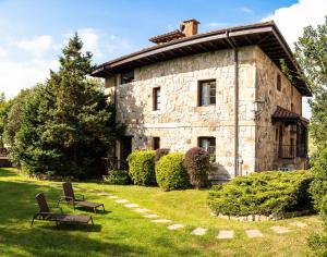 a stone building with two chairs in front of it at Apartamentos Los Hidalgos in Santillana del Mar