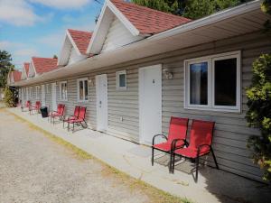 uma fila de cadeiras vermelhas ao lado de uma casa em Motel Abricafé em Stoneham