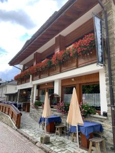 un edificio con mesas y sombrillas delante en Hotel Capriolo, en Madesimo