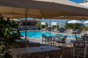 a pool with tables and chairs and an umbrella at Kastro Maini in Areopolis