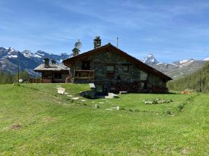 una casa su una collina erbosa vicino a una montagna di CHALET GORRET CHENEIL a Valtournenche