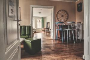 een woonkamer met een tafel en stoelen en een klok bij OPERA Hostel in Erfurt