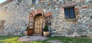 - un vieux bâtiment en pierre avec une porte en bois dans l'établissement Masia Can Bachs, à Sant Pere de Vilamajor