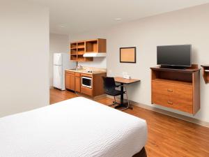 Schlafzimmer mit einem Bett und einem Schreibtisch mit einem TV in der Unterkunft WoodSpring Suites Merrillville in Merrillville