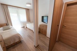 a bedroom with a bed and a television and a door at Penzion Livada in Kranjska Gora