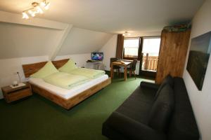 1 dormitorio con cama, sofá y escritorio en Café-Pension Feldbergblick, en Titisee-Neustadt