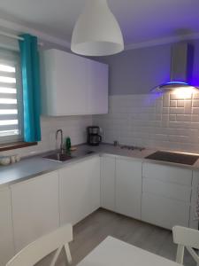 uma cozinha com armários brancos e um tecto azul em Apartament FAMILY- klimatyzacja em Oświęcim