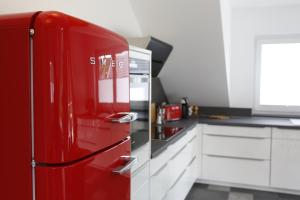 a red refrigerator in a kitchen with white cabinets at Rooftop Moselsuite in Cochem