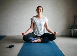 Una donna seduta in posa per yoga su un tappetino di Hotel Landhafen a Niebüll