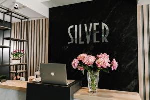 a vase of pink flowers on a desk with a laptop at Готельно-рестораний комплекс Silver in Ivano-Frankivsʼk