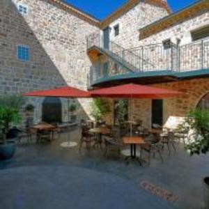 eine Terrasse mit Tischen und roten Sonnenschirmen vor einem Gebäude in der Unterkunft Le Mas de Baume in Rosières