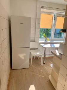 een keuken met een witte koelkast en een tafel bij Centro Apartamentai in Zarasai