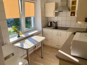 een keuken met witte kasten en een tafel en een raam bij Centro Apartamentai in Zarasai