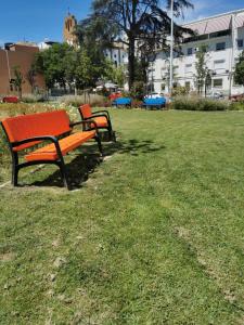 twee parkbanken in het gras in een park bij Apartamento Luxury Home Huelva Zona centro in Huelva