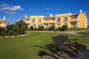 un banc devant un grand bâtiment jaune dans l'établissement Colina da Lapa & Villas, à Carvoeiro