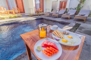 una mesa con fruta y zumo junto a una piscina en Cening Ayu Sanur, en Sanur