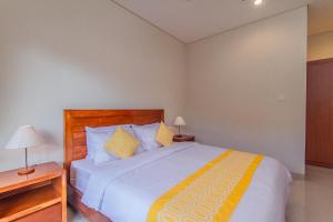 1 dormitorio con 1 cama grande con sábanas blancas y amarillas en Cening Ayu Sanur, en Sanur