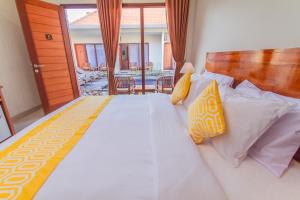 Un dormitorio con una cama grande con almohadas amarillas y blancas en Cening Ayu Sanur, en Sanur