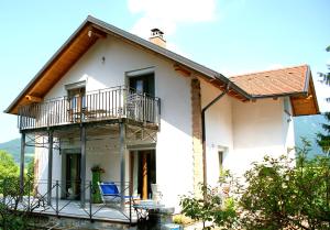 Dieses weiße Haus verfügt über einen Balkon und eine Veranda. in der Unterkunft Apartments Leni in Postojna