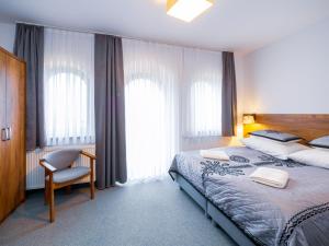 a bedroom with a bed and a chair and windows at Strama Kościelisko in Kościelisko