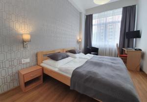 een slaapkamer met een bed, een bureau en een raam bij Hotel Preveza in Spišská Nová Ves