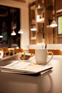 eine Tasse Kaffee auf einem Tisch mit einer Zeitung in der Unterkunft Holiday Inn Express Munich - Olympiapark, an IHG Hotel in München