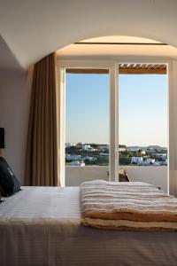 een slaapkamer met een bed en een groot raam bij Vrachos Suites Mykonos in Mykonos-stad